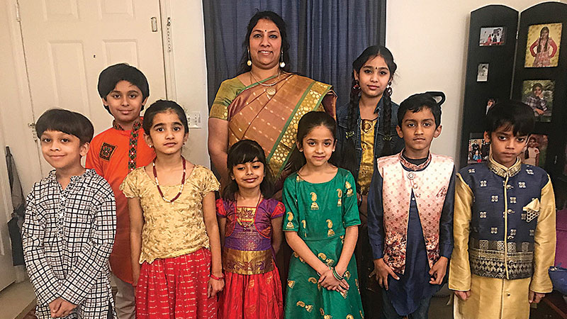 Students wearing traditional performance attire, which includes Pavadai and Chattai (long skirt and top) for girls and Kurta (long shirt) and jeans for boys