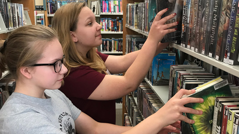 Youth Advisory Board members Abby and Emmy Omlor making sure the teen shelves are organized correctly.
