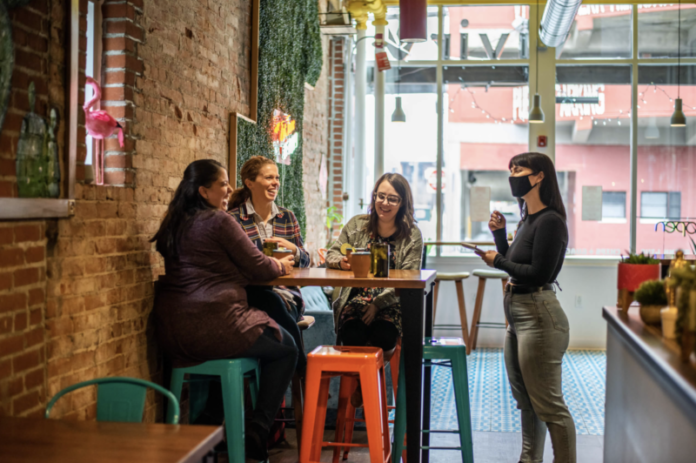 Three women sit and a waitress takes their order